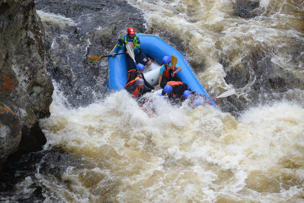 Image of a raft partially-submerged in a pocket of rapids
