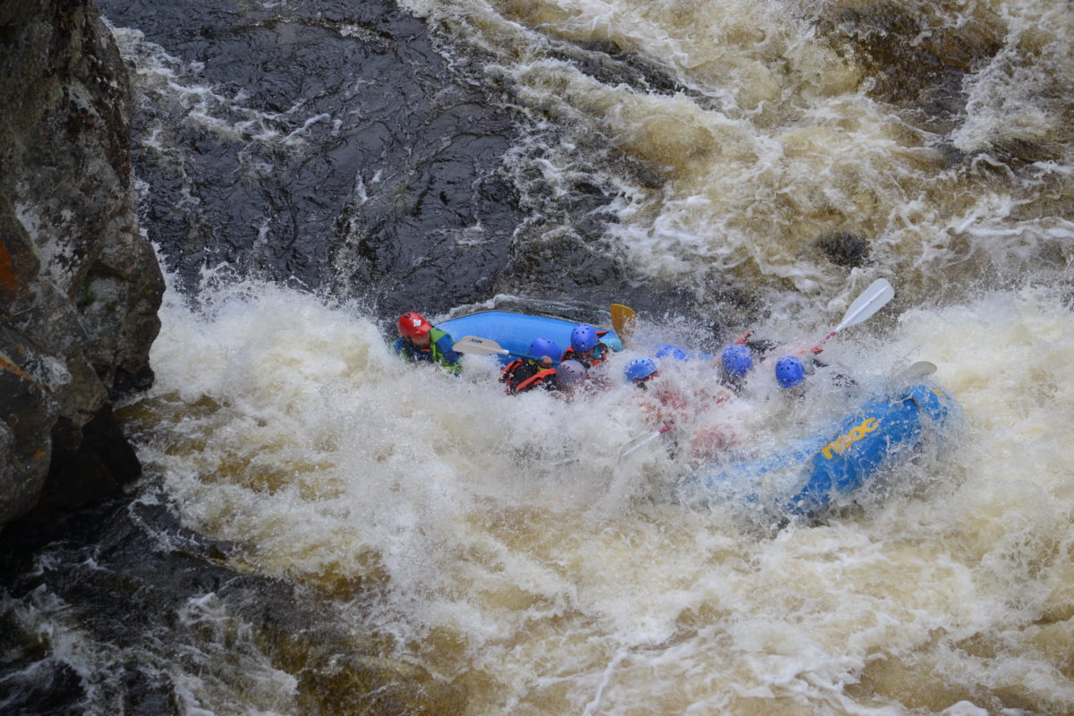 Image of a raft coming out of a pocket of rapids minus one blue helmet